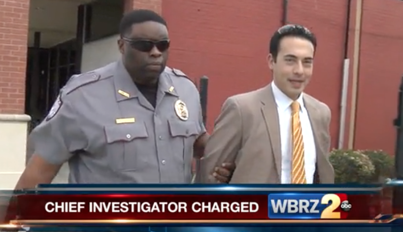 A reporter being led away in handcuffs by a uniformed officer. A reporter being led away in handcuffs by a uniformed officer.